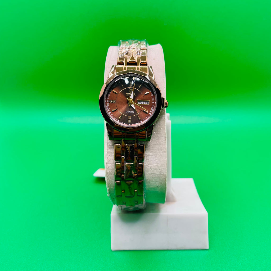 Gold watch on a white stand against a green background
