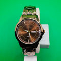 Watch with a brown face and silver band on a green background